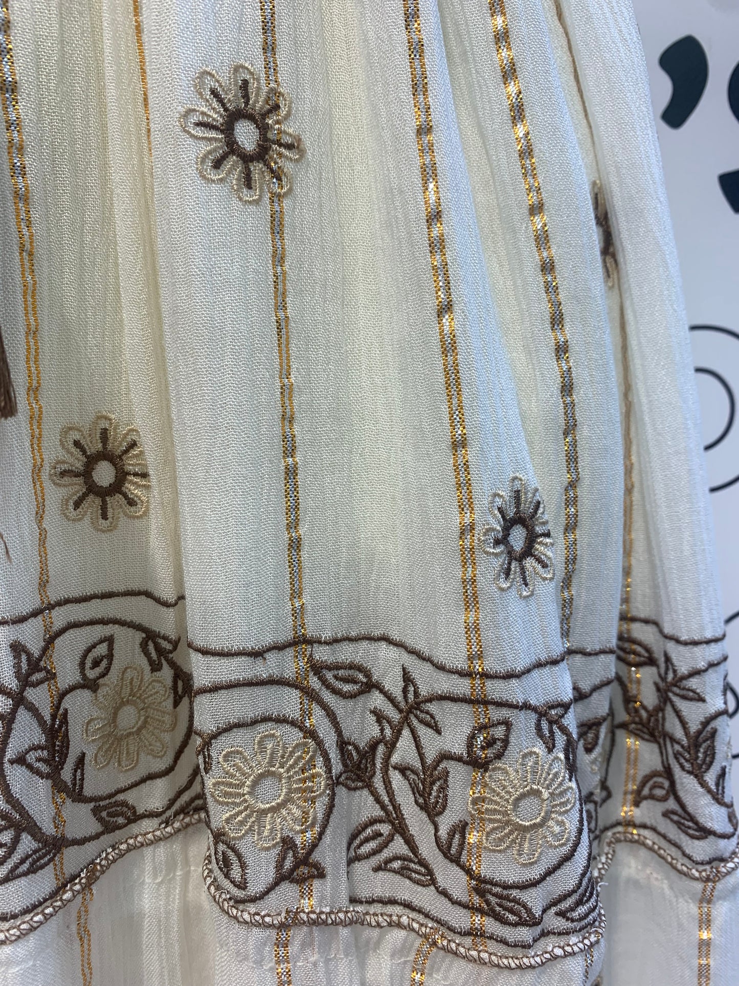 Vestido largo blanco con bordados marrón y beige.